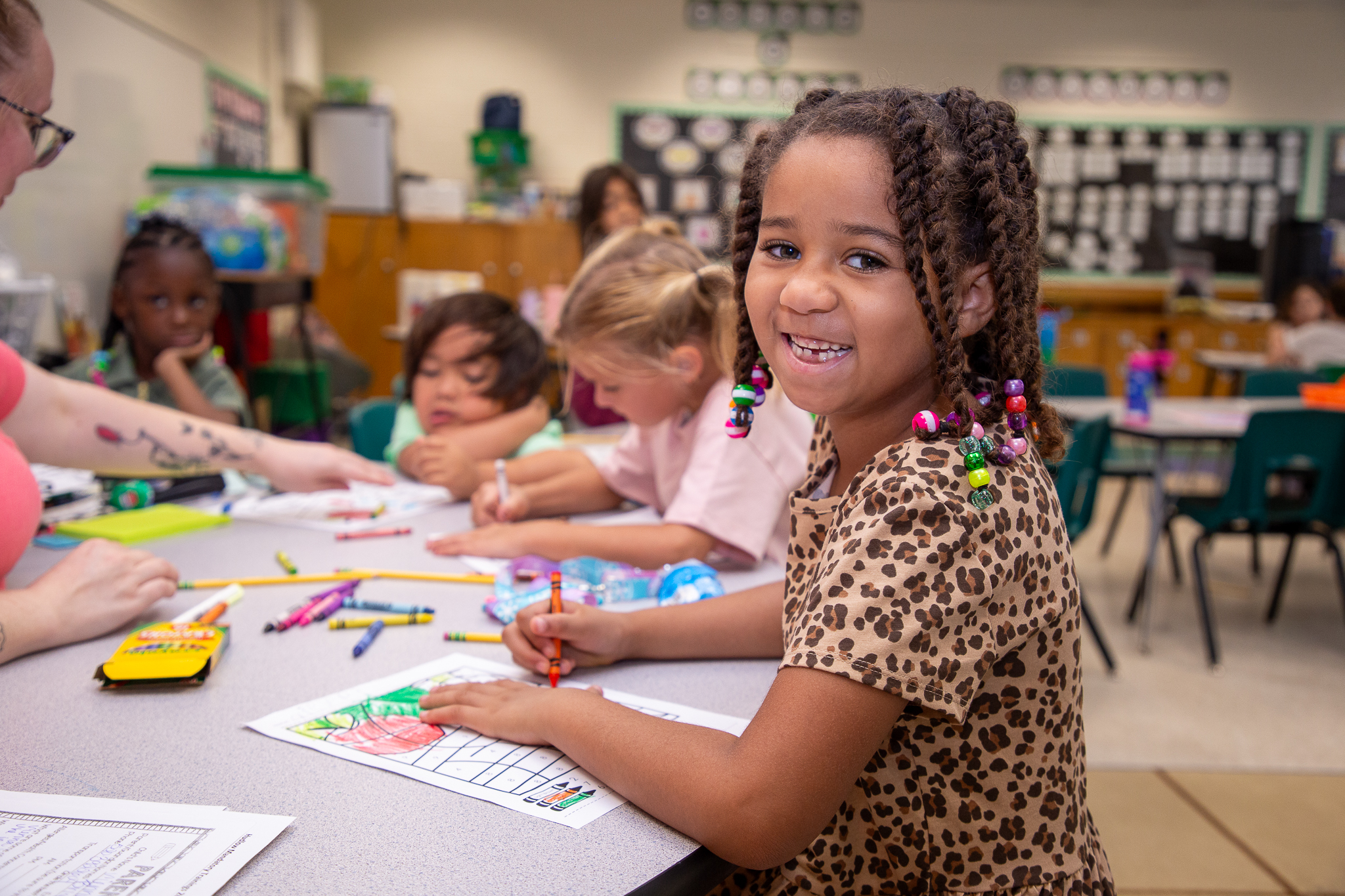 A little girl smiles as she colors on the second day of school