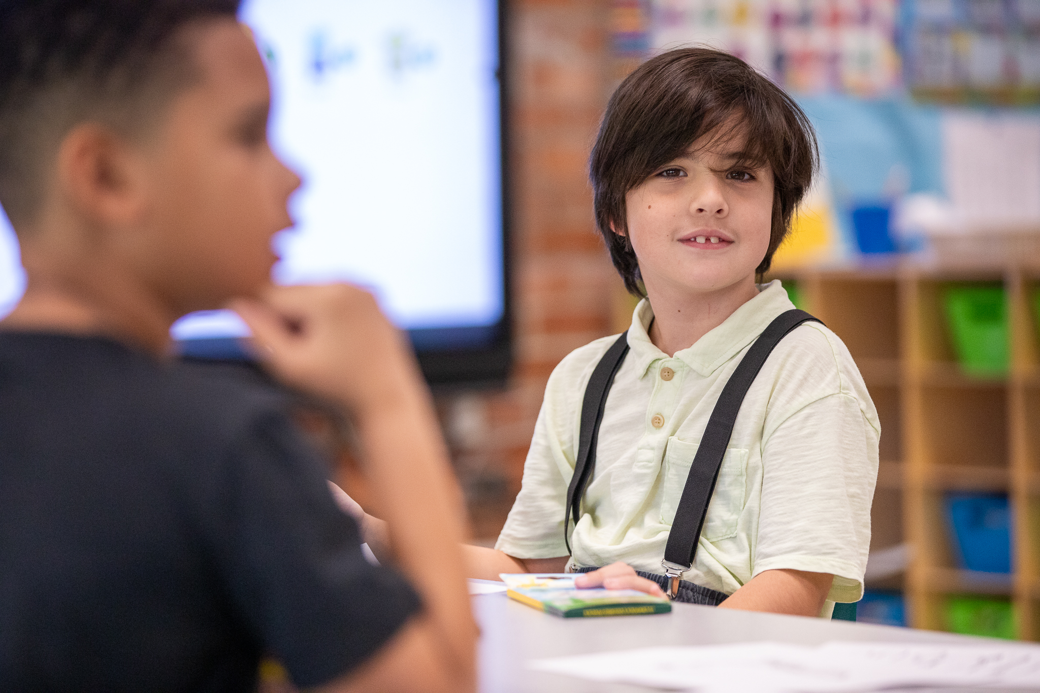 A little boy smiles at his desk on the second day of school