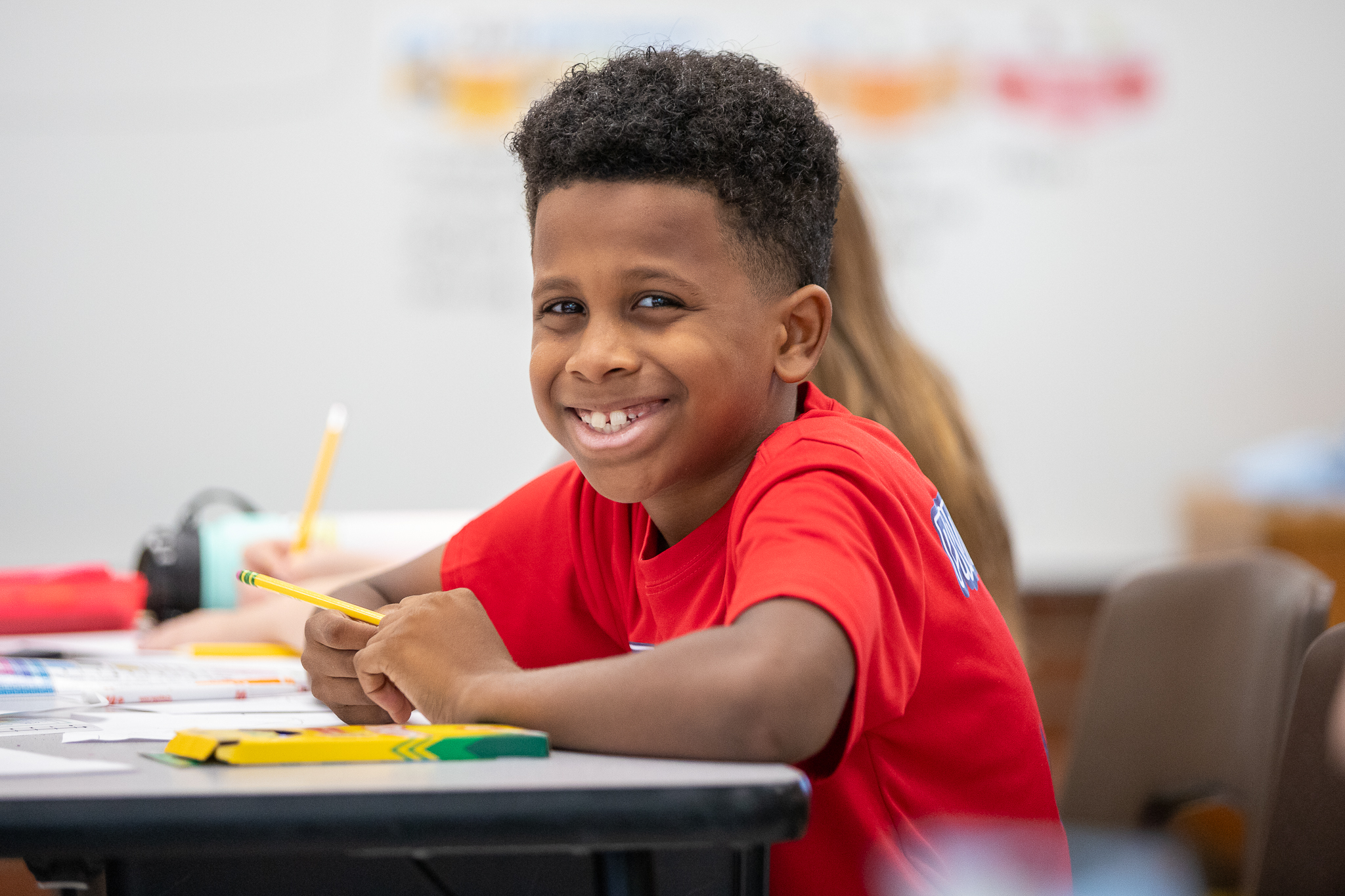 A little boy smiles at his desk