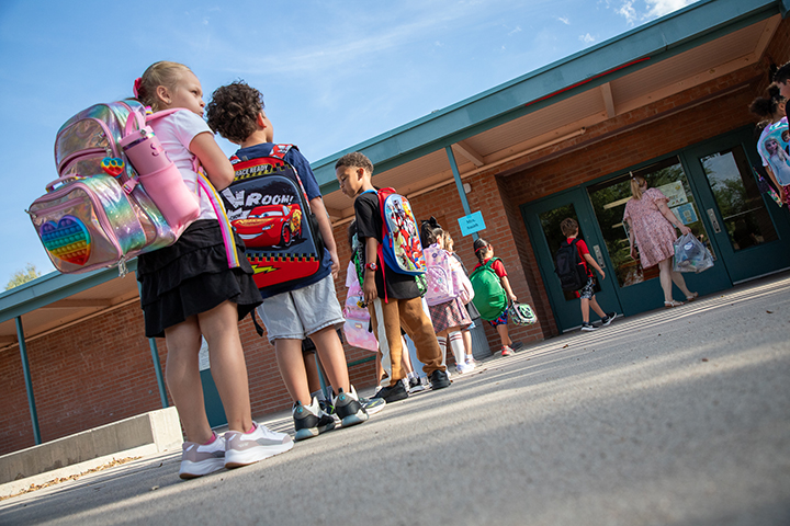 A group of students line up outside school with their backpacks on